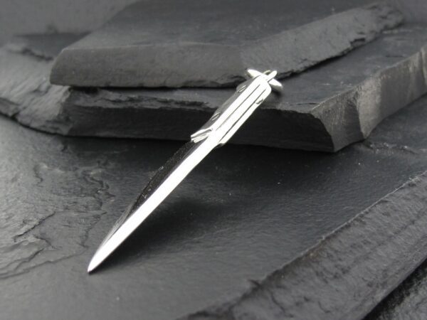 Elegant silver pen on dark slate background.