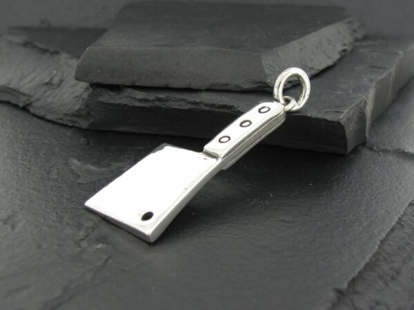 Silver cleaver-shaped pendant on dark stone background.