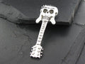 Metal guitar pendant with a skull design on top, placed on a dark stone surface.