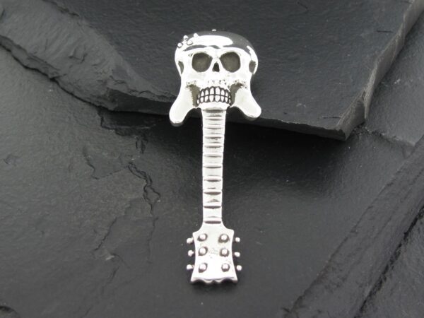 A silver pendant shaped like a stylized skull and guitar.