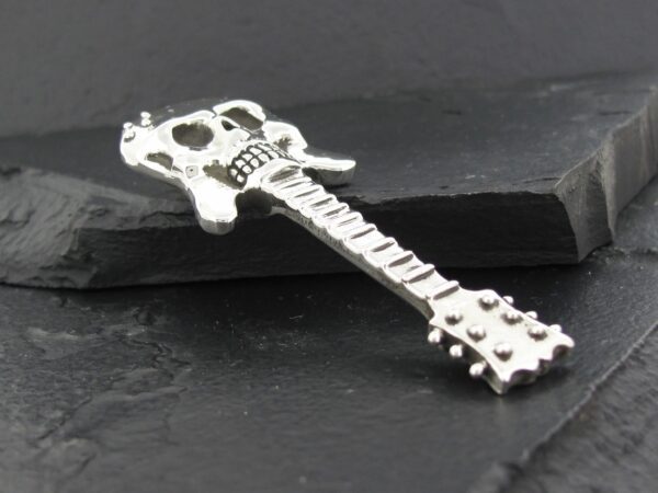 Silver guitar-shaped pendant on a black surface.