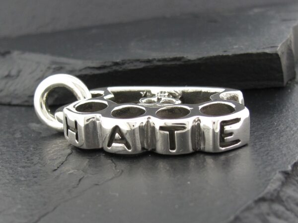 Close-up of a silver pendant spelling 'NATIE'.