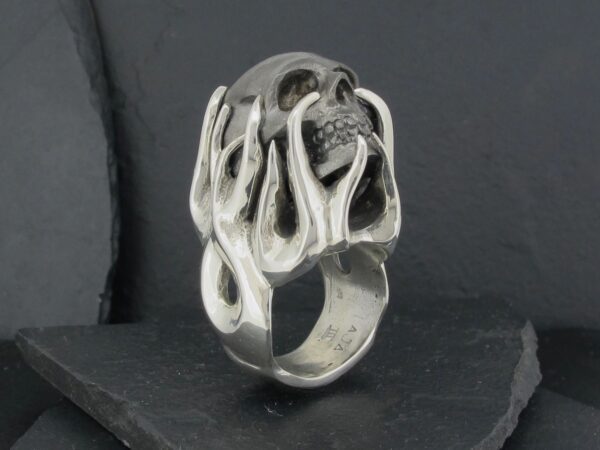 Silver ring with an intricate skeletal flame design.