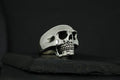 A detailed silver skull ring on a black background.