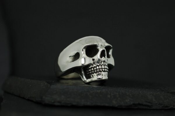 A detailed silver skull ring on a black background.