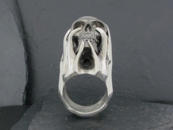 A skull-shaped silver ring with detailed carvings.