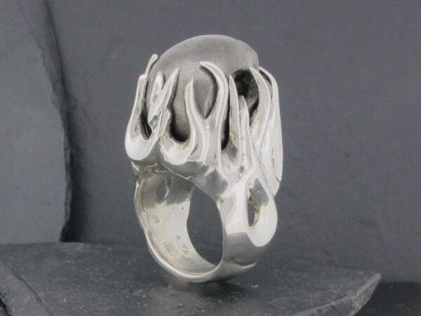 Silver ring with an abstract, wavy design on top.