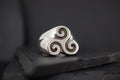 Silver ring with a triple spiral design on a dark surface.