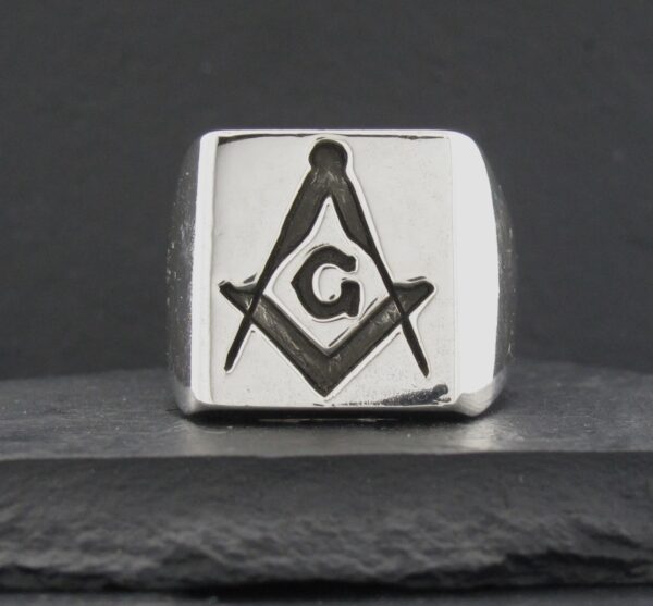 A silver ring with the Masonic square and compass symbol and a 'G' in the center.