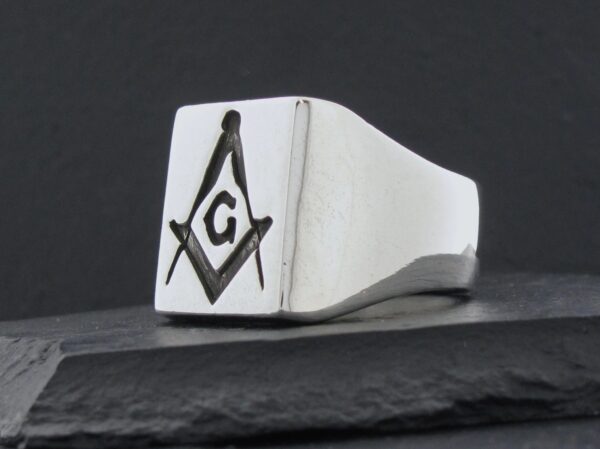 Silver ring with a Masonic square and compass symbol.
