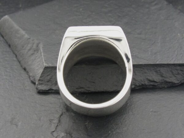 Silver ring with a hollow center on a dark stone surface.