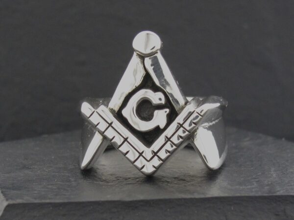 Silver Freemason symbol featuring a compass, square, and letter G.