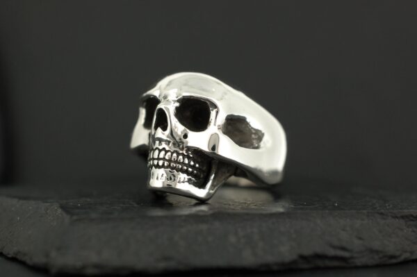 A silver skull ring with detailed teeth and hollow eyes.