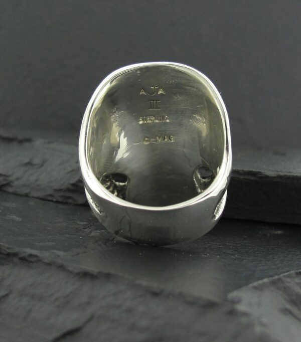 A close-up of a silver ring with engraved markings inside.