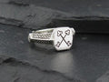 Silver ring with crossed keys engraved on its square face.