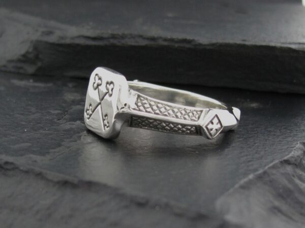 Silver ring with intricate geometric and symbolic engravings.