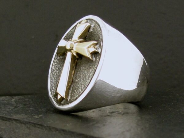 A silver ring featuring a raised cross on an oval face.