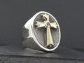 Silver ring with a cross and red gemstone centerpiece.