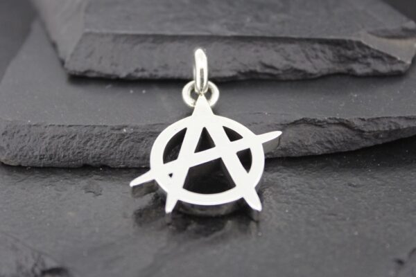 Silver anarchy symbol pendant on a dark textured background.