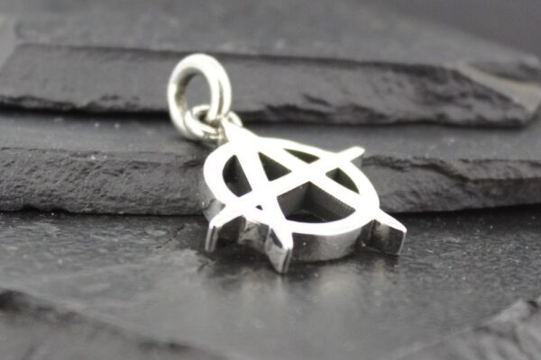 Silver anarchy symbol pendant on a dark surface.
