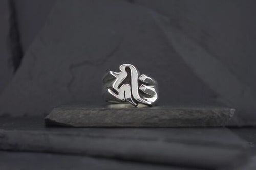 Silver ring with a gothic-style letter design on a dark surface.