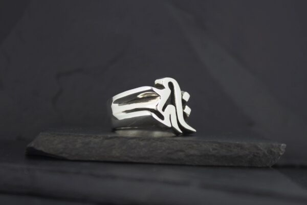 Silver ring with a unique abstract design on a dark background.
