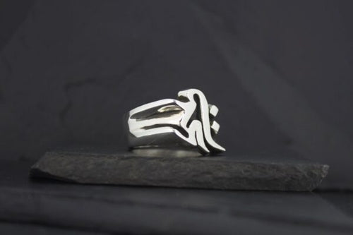 Silver ring with a unique abstract design on a dark background.