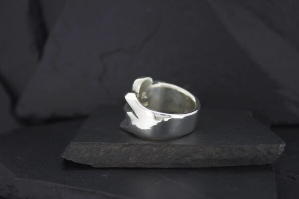 A sleek silver ring with a modern, abstract design.