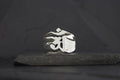 Silver ring with a raised Om symbol on a dark background.