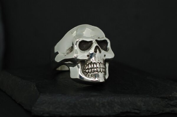 A silver skull-shaped ring with detailed teeth and eye sockets.