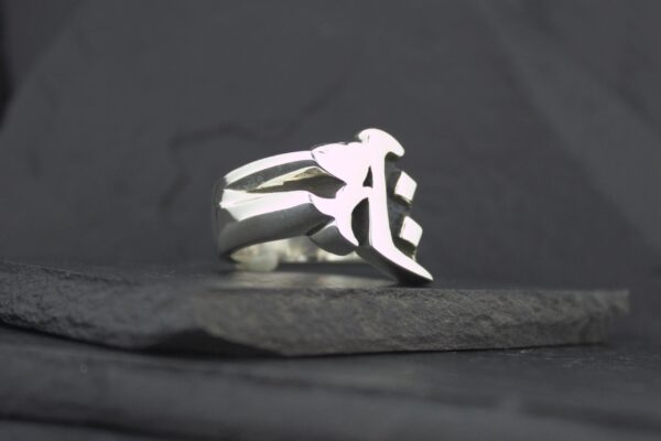 Silver ring with an abstract design on a dark surface.