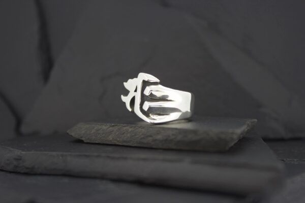 Silver ring with an abstract design on a black surface.