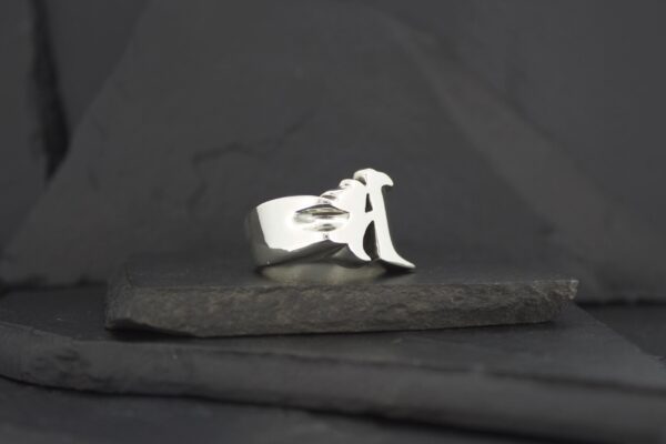 Silver ring featuring a stylized letter 'A'.