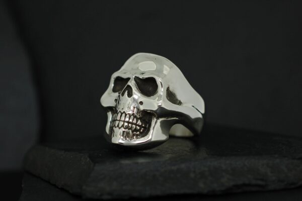 A silver ring shaped like a skull against a black background.