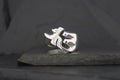 Silver phoenix ring on dark stone surface.