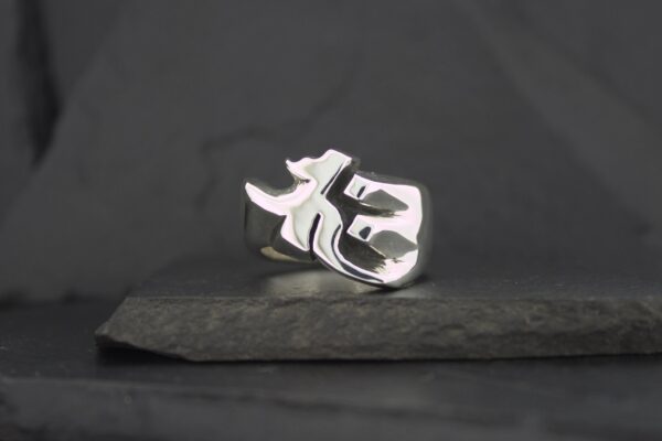 Silver phoenix ring on dark stone surface.