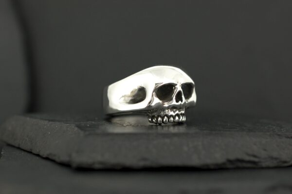 A silver skull-shaped ring on a dark surface.