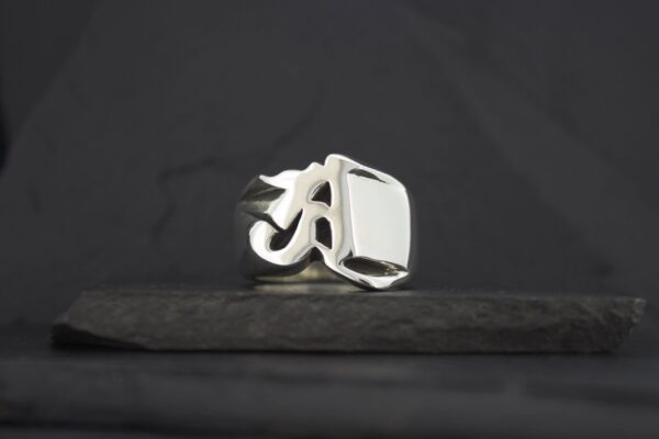 A silver ring with a bold, rectangular face on a dark background.