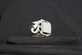 A silver ring with a bold, rectangular face on a dark background.