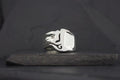 A silver ring with a flame design on a dark surface.