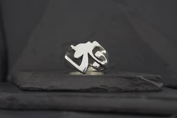 A silver ring with a unique geometric design on a dark surface.
