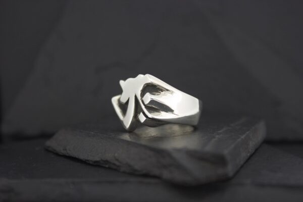 A silver ring with a triangular design on a dark surface.
