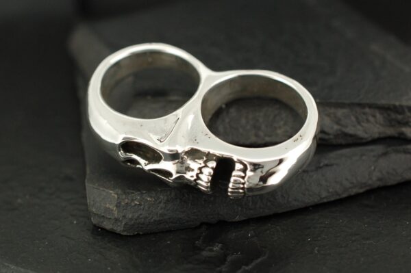 Silver double-finger ring featuring a detailed skull design.