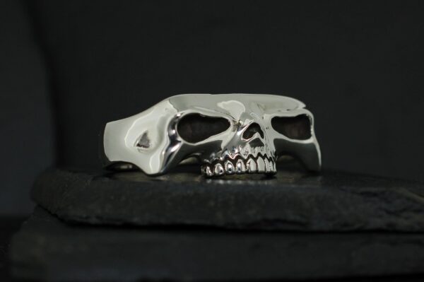 A silver ring shaped like a skull with detailed teeth and hollow eyes.