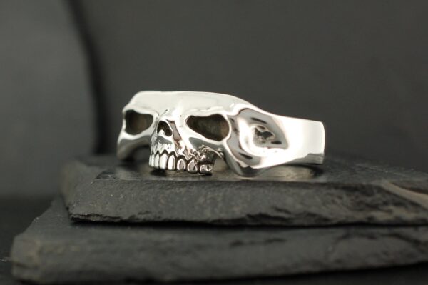 Silver skull-shaped ring with detailed teeth and hollow eyes.