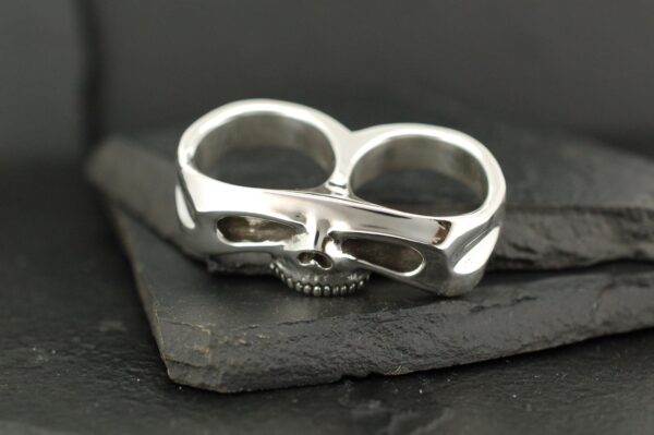 Silver double-finger ring with a skull design.