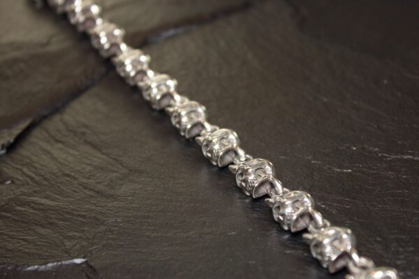 Close-up of a silver bracelet with intricate links on a dark surface.