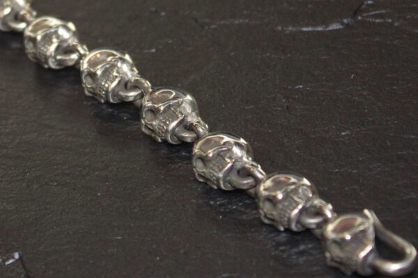 Close-up of a silver bracelet with intricately designed skull links.