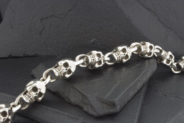 A silver bracelet made of interconnected skulls.