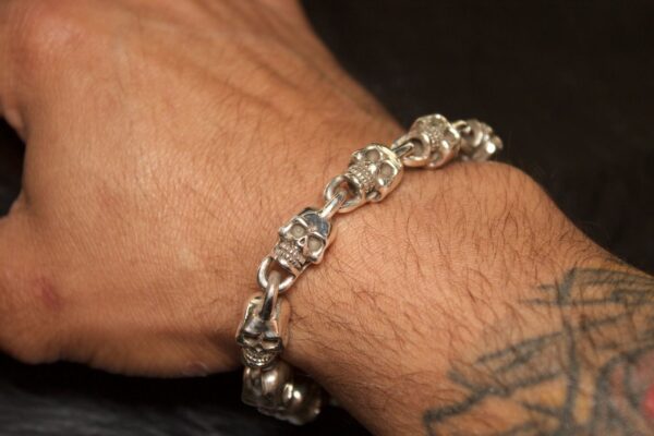 Silver skull bracelet worn on a wrist with a tattoo.